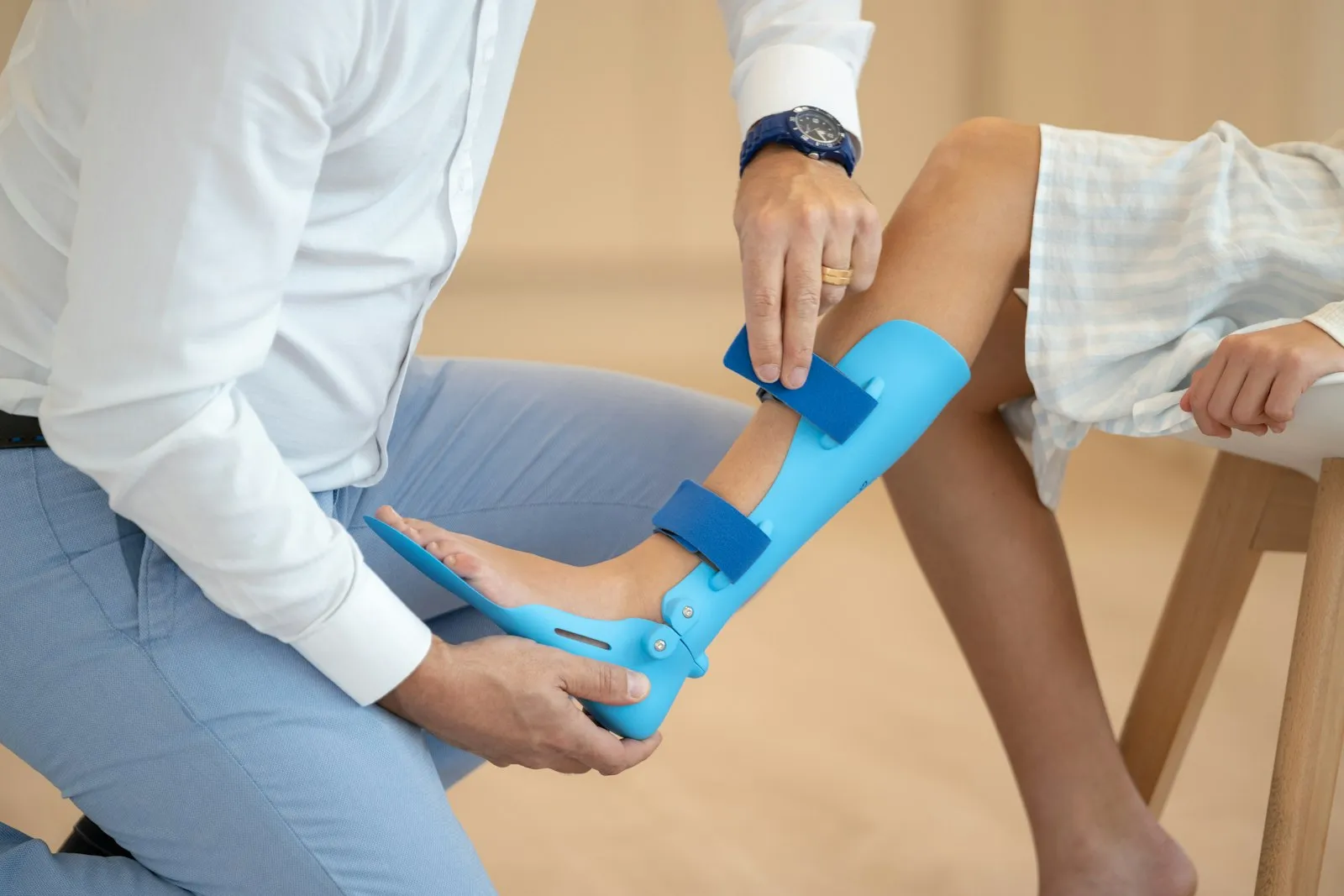 An orthopedic clinician fitting a leg brace on a seated patient.