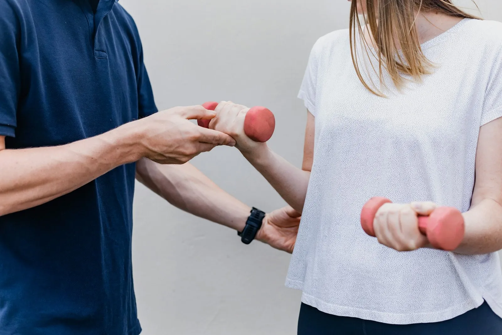 A physical therapist guiding a patient through a light-dumbbell exercise.
